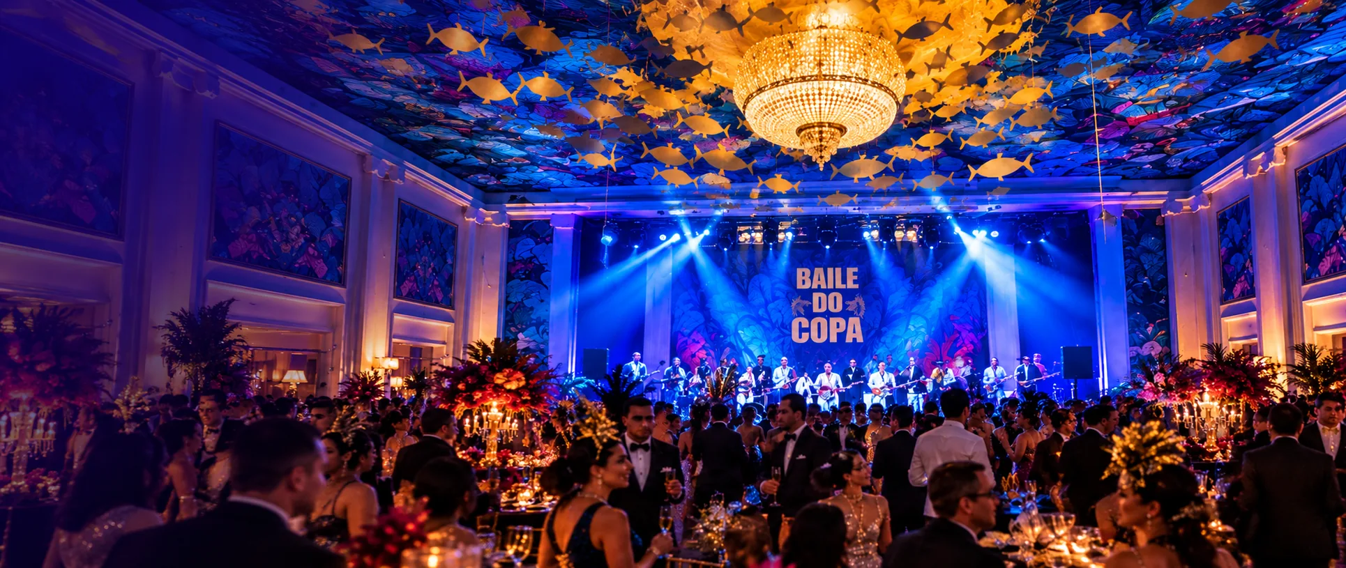 Guests toasting beneath the golden fish-ceiling installation and chandelier on the Copa Ball dance floor