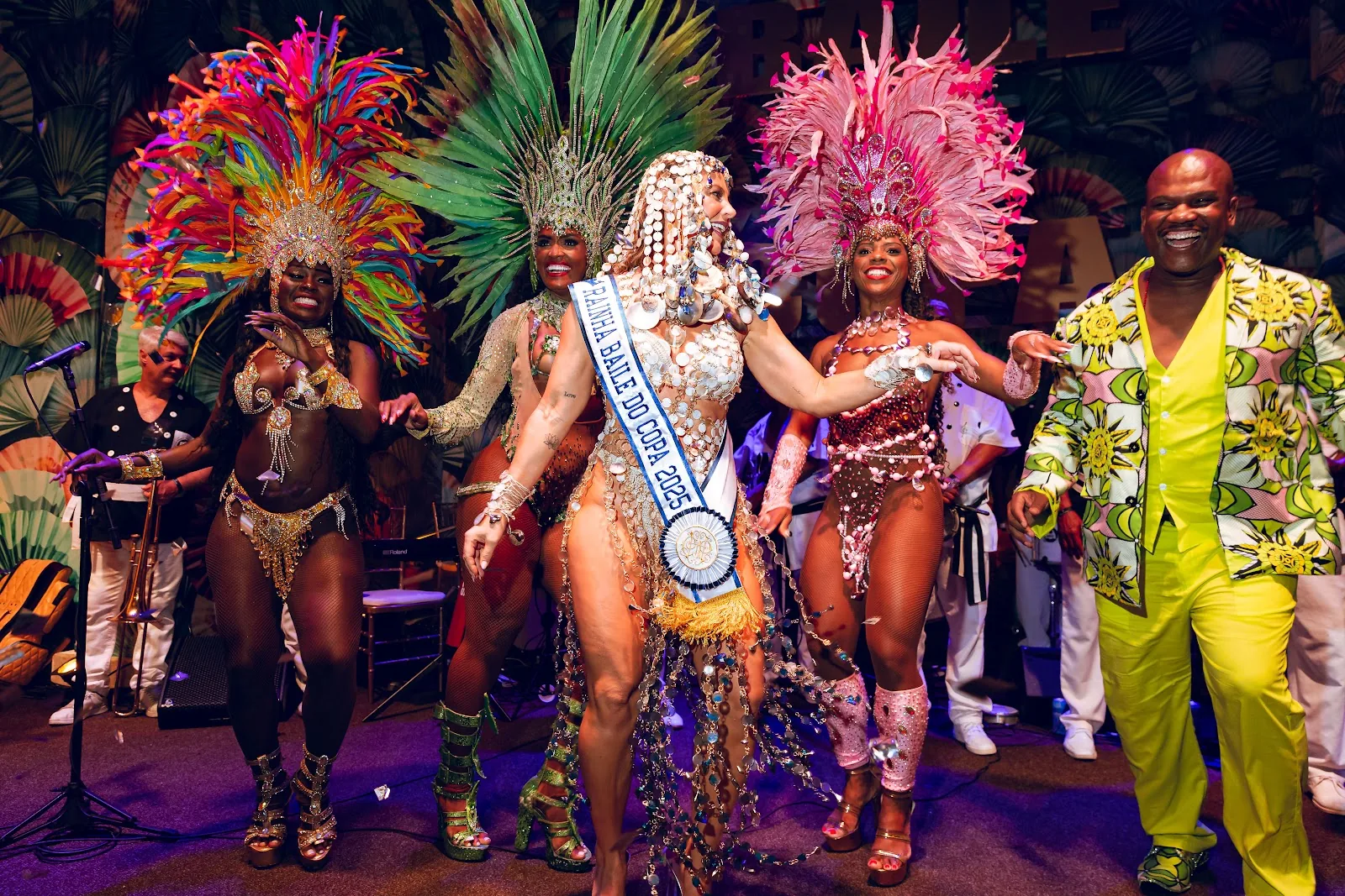 Samba dancers in feathered costumes performing on stage at the Baile do Copa